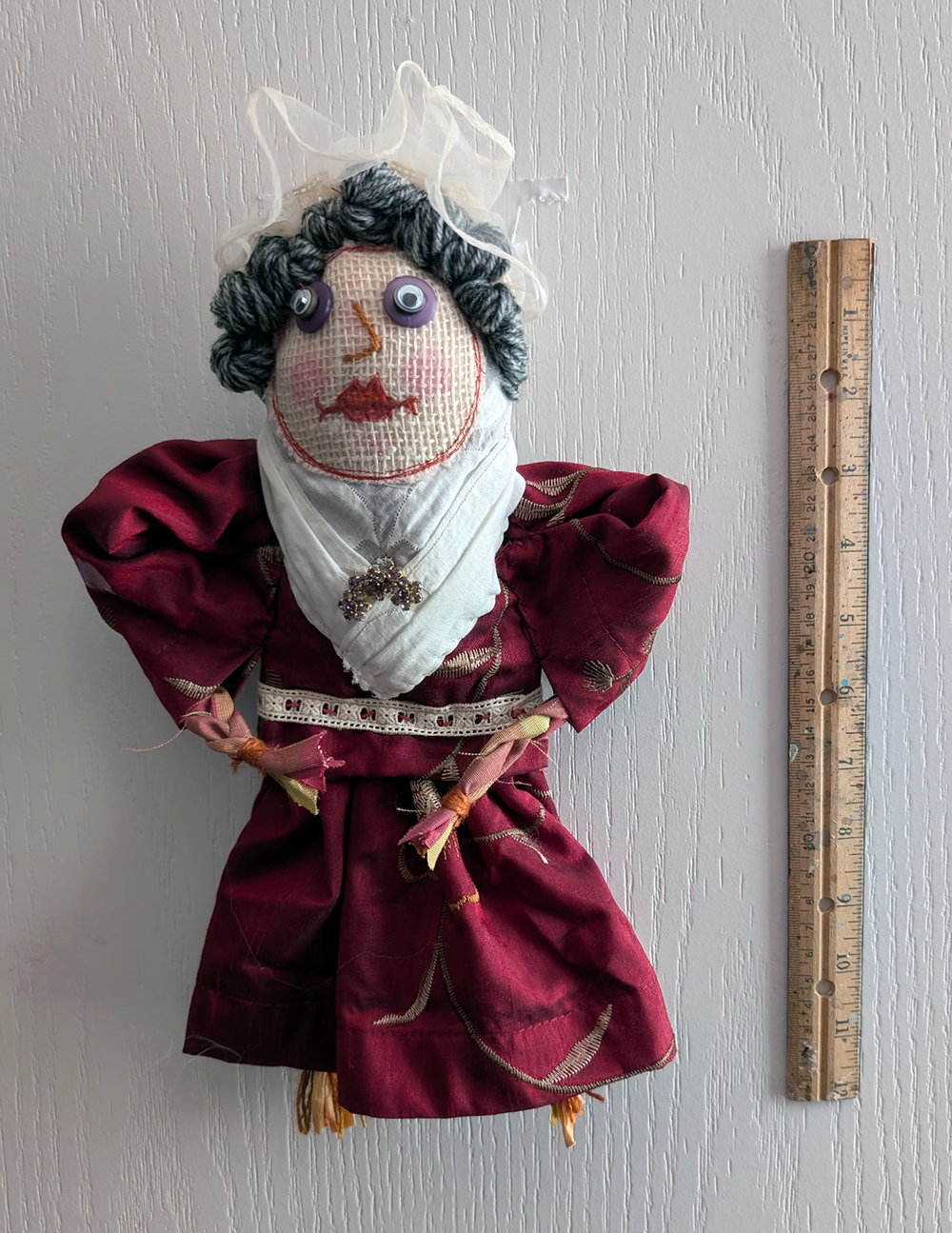 A handmade Scrappy Doll standing beside a 12-inch wooden ruler, showing the doll is approximately one foot tall